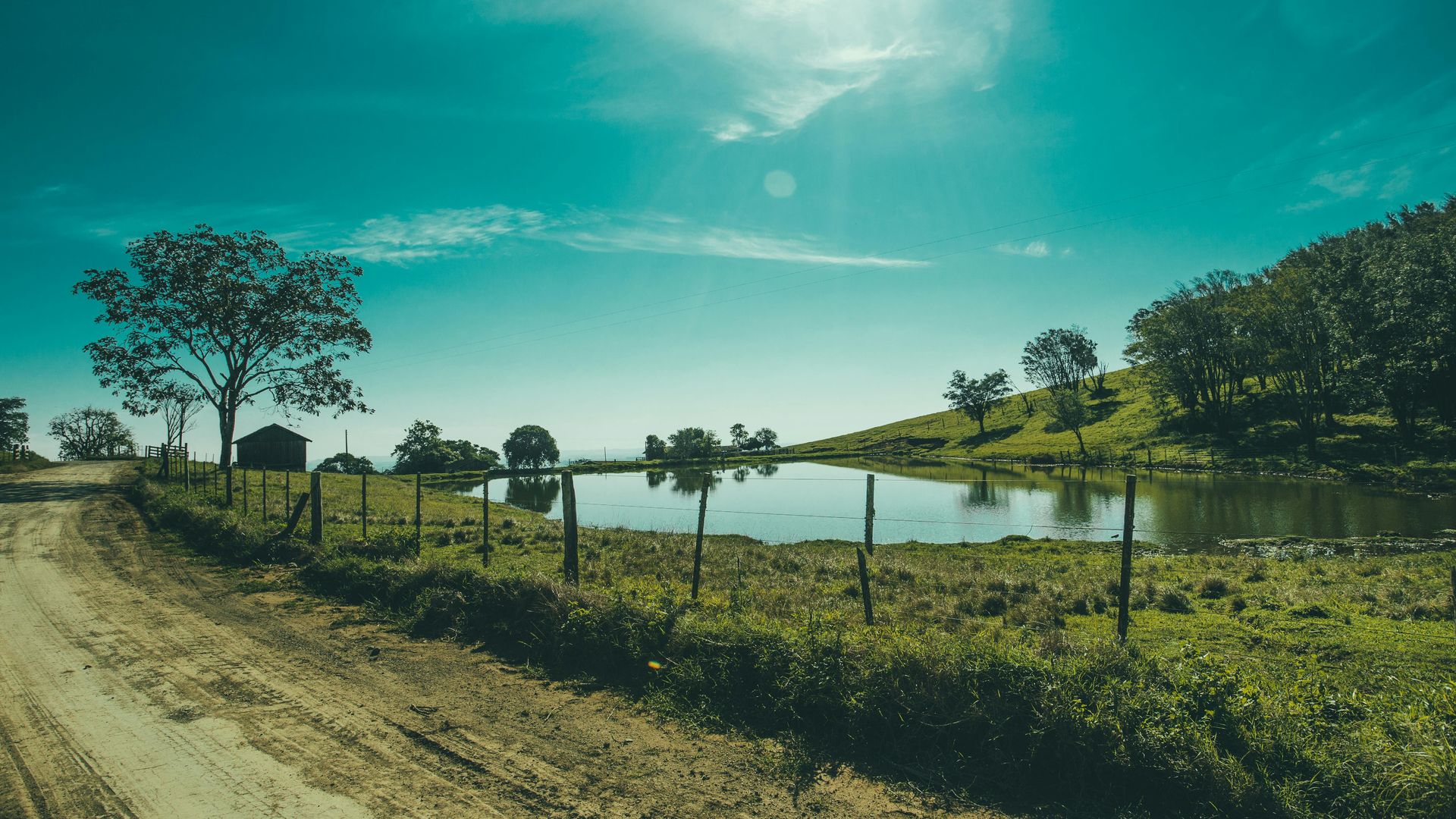 Texas Hill Country ranch road with pond at sunset