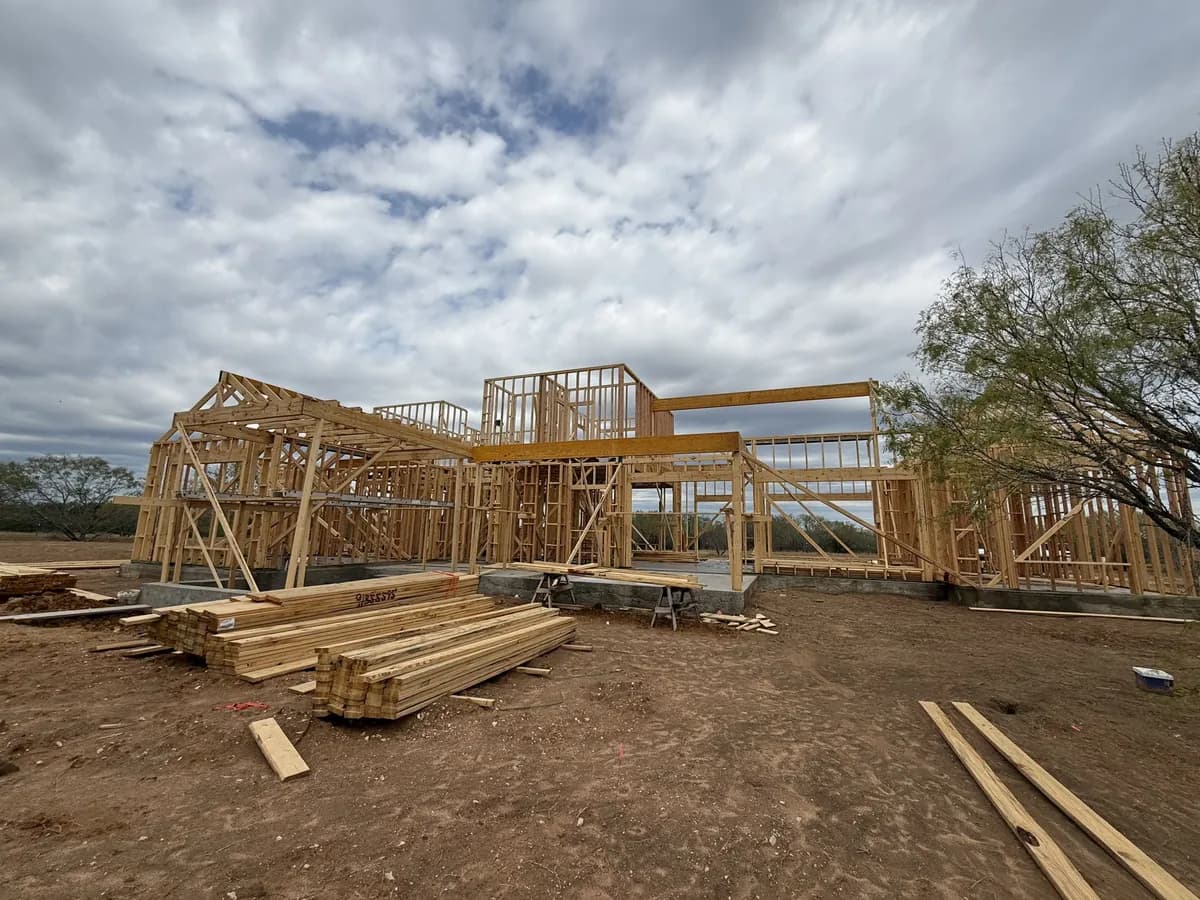 Custom home framing rising against a big cloudy Texas sky